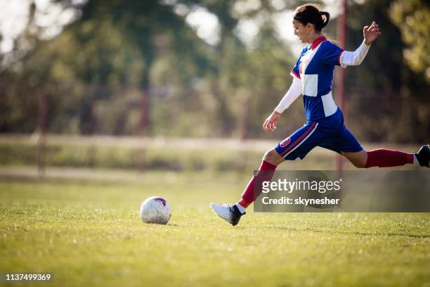 teenage girl about to kick soccer ball on a playing field. - rematar à baliza imagens e fotografias de stock