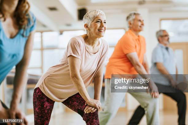 gente atlética madura haciendo ejercicios de relajación mientras practica en el club de salud. - exercise class fotografías e imágenes de stock