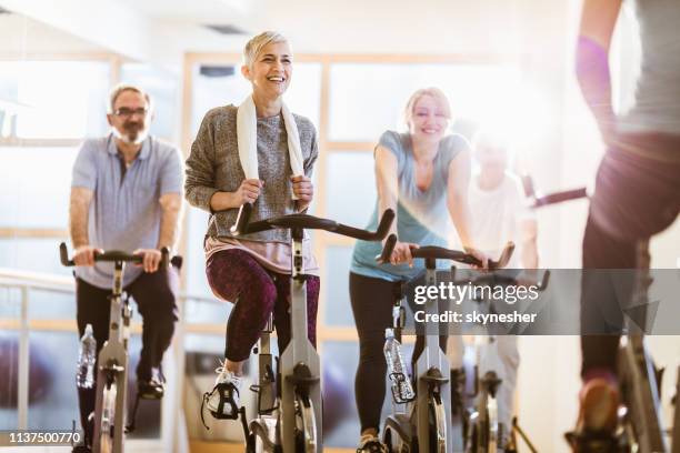 groupe d'aînés actifs ayant la classe de filature avec un instructeur dans une salle de gym. - cours de spinning photos et images de collection