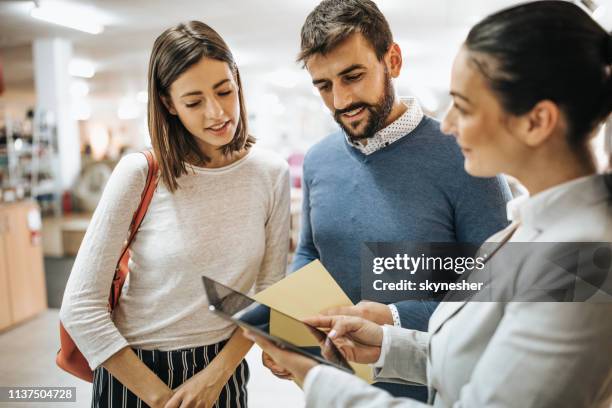 young couple and saleswoman using touchpad at furniture store. - loja de móveis imagens e fotografias de stock