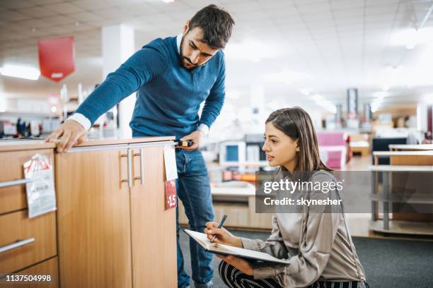 young couple shopping new furniture and taking measurements at the store. - office supply stock pictures, royalty-free photos & images