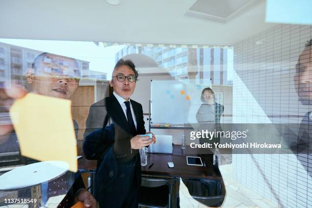 business colleagues having informal project meeting at office. - chigasaki stock pictures, royalty-free photos & images