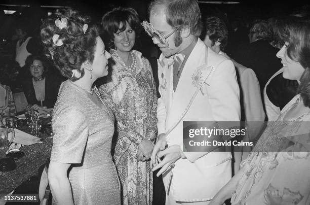 Princess Margaret speaking to singer-songwriter Elton John at an event in 1974. On the right is actress Nanette Newman.
