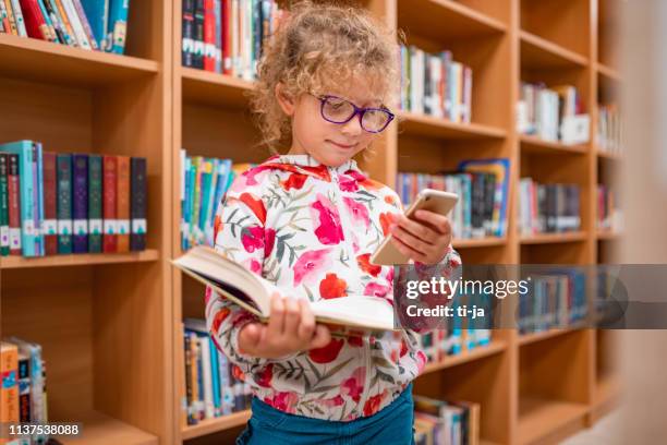 little girl in a library using mobile phone - ljubljana library stock pictures, royalty-free photos & images