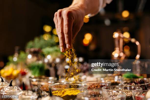 hand streut currypulver oder kurkuma in schalen - orientalisch gewürze - strooisels stockfoto's en -beelden