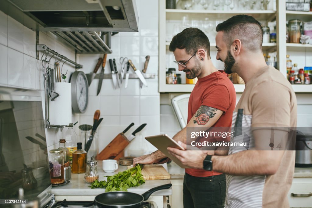 Man standing by boyfriend preparing food at home