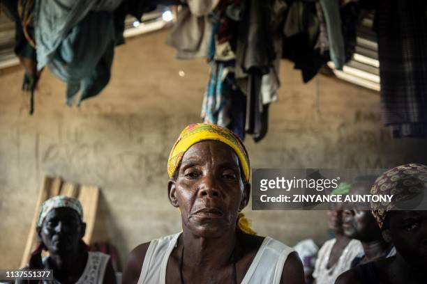 Clothes hang above Maderina Jose, 65-years-old, as she sit in a classroom with other women sheltered at Guara-Guara Primary School, Buzi District,...