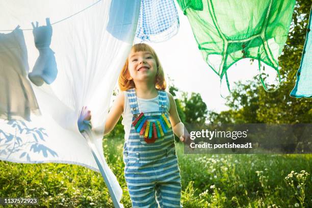 cute blond boy looking through laundry - clothesline stock pictures, royalty-free photos & images