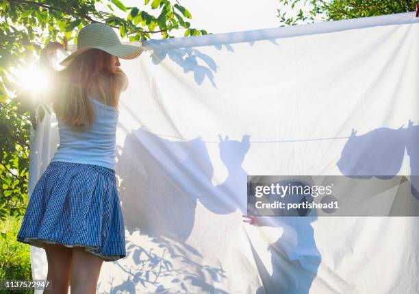 mother and her son hanging laundry on a clothes line - draped sheet stock pictures, royalty-free photos & images