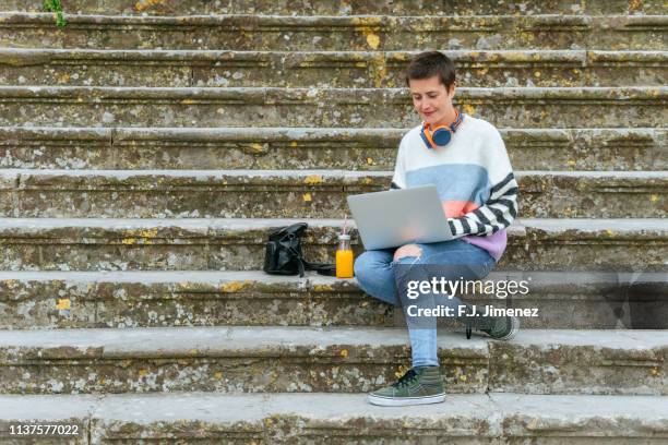 woman using laptop on the street - androgynous stock-fotos und bilder