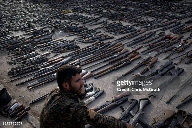An SDF fighter looks over seized ISIL weapons that were found in the last stronghold of the extremist group as they were displayed at an SDF base on...
