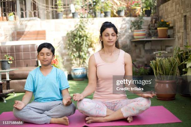 mother and son meditating on exercise mat - mom son yoga stock pictures, royalty-free photos & images