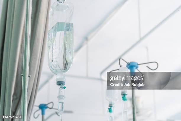 saline drip hanging on metal hook against wall in hospital - infused 個照片及圖片檔