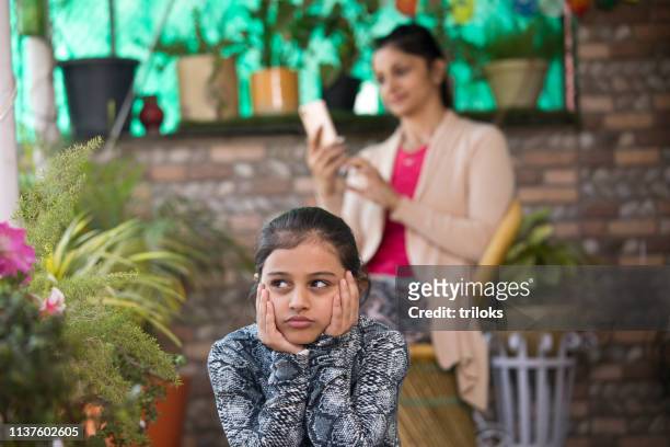 bored girl with mother using mobile phone - parent stock pictures, royalty-free photos & images