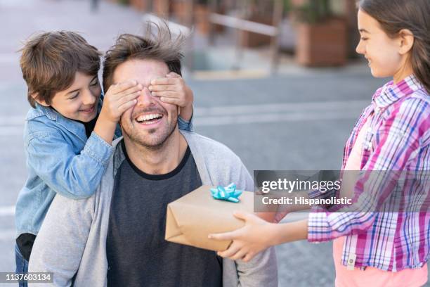 söt snart täcker sin fars ögon medan dottern håller en present till fars dag - fathers day bildbanksfoton och bilder