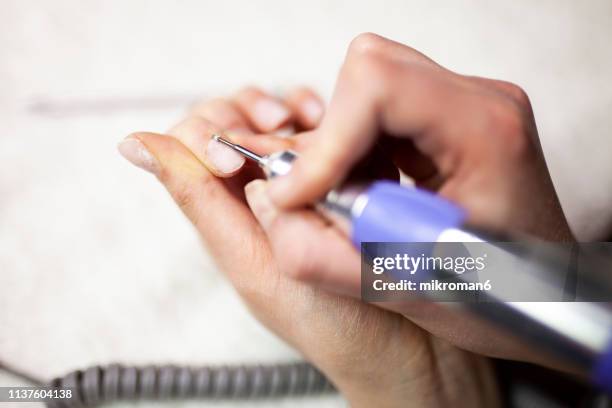 woman doing gel/acrylic nails on herself - nagelfeile stock-fotos und bilder