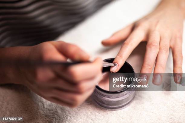 woman doing gel/acrylic nails on herself - gel nail polish stock pictures, royalty-free photos & images