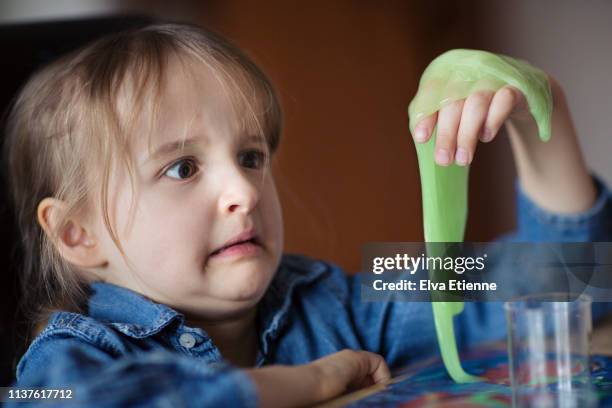 child (6-7) looking at novelty green slime in disgust - goop stockfoto's en -beelden