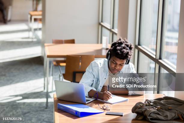 teenage boy studiert in schulbibliothek - school notebook stock-fotos und bilder