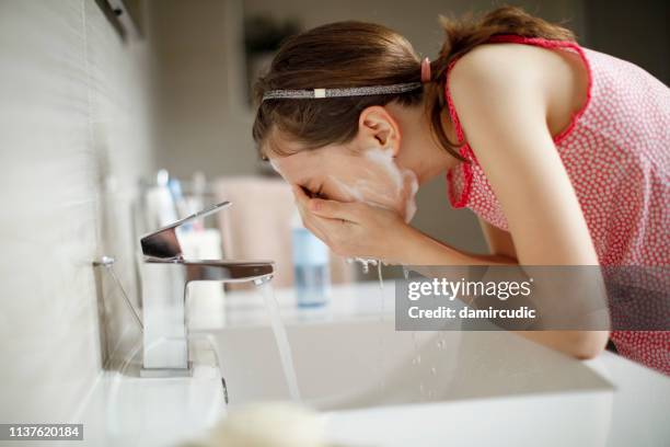 teenager-mädchen waschen ihr gesicht mit wasser - gesichtsreinigung stock-fotos und bilder