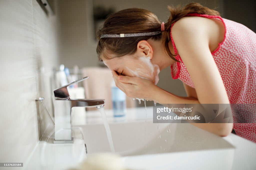 Teenage girl washing her face with water