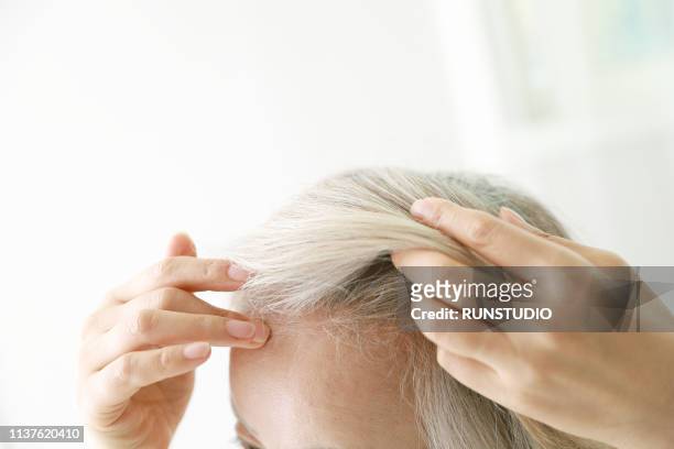 senior woman checking hair - haaruitval stockfoto's en -beelden