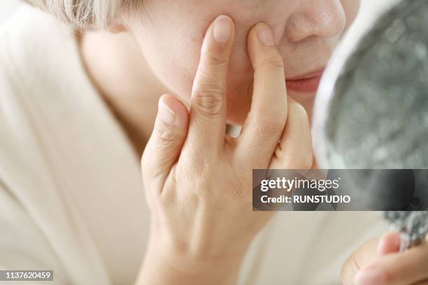 senior woman checking wrinkled face - complexion foto e immagini stock