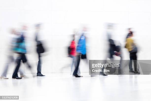 große gruppe von menschen, die auf weißem flur, motion blur-effekt laufen - airport shop stock-fotos und bilder