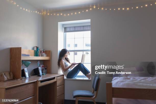 young woman college student in her dorm room with laptop - studentenflats stockfoto's en -beelden