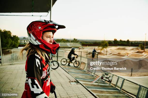 portrait of female bmx racer looking at track before race start - ciclismo bmx imagens e fotografias de stock