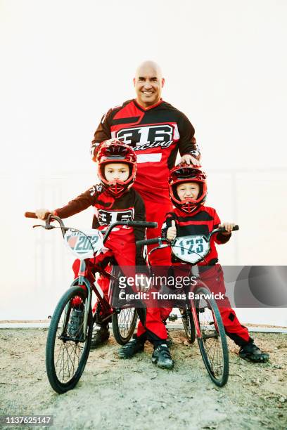 Portrait of smiling father and sons in front of white background before BMX race