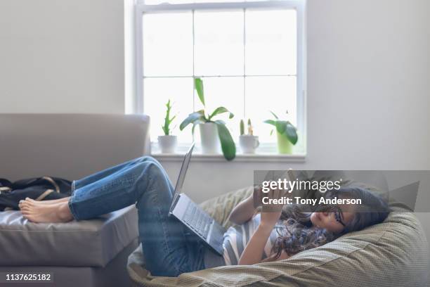 young woman college student in her dorm room with phone and laptop - bean bags stock pictures, royalty-free photos & images