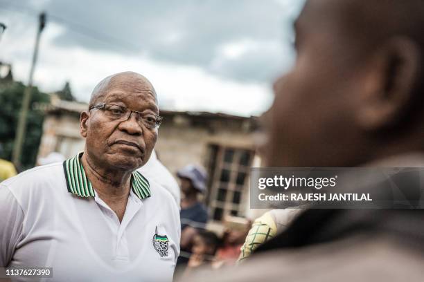 Former South African President and former president of the ruling party African National Congress Jacob Zuma listens to local resident Sandile Ngcobo...