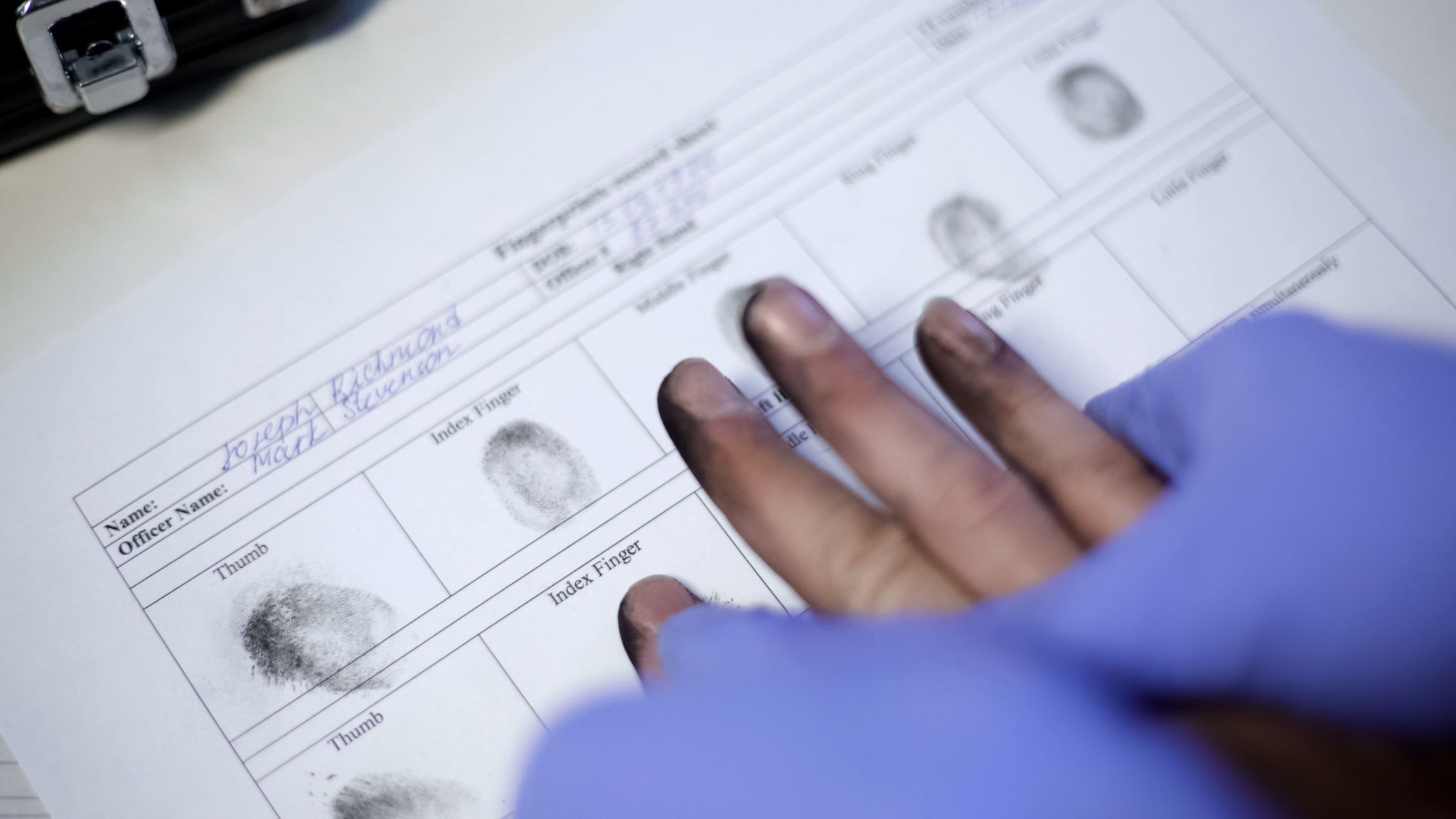 Police officer in exam gloves taking fingerprints from suspect, hands closeup Police officer in exam gloves taking fingerprints from suspect, hands closeup