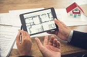 Real estate agent presenting floor plan to customer on tablet computer