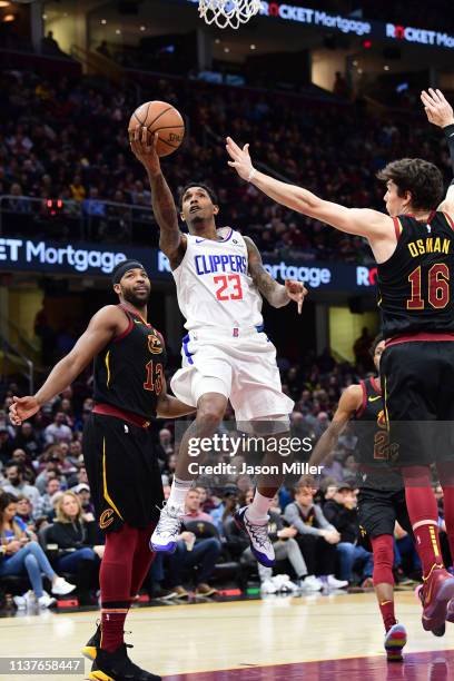 Lou Williams of the LA Clippers shoots over Cedi Osman of the Cleveland Cavaliers during the first half at Quicken Loans Arena on March 22, 2019 in...