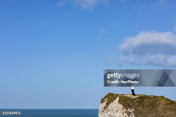 Etretat, Normandy, France, March 25, 2019. A woman looks at the ocean from the d aval cliff in good weather. Etretat, Normandie, France, le 25 mars...