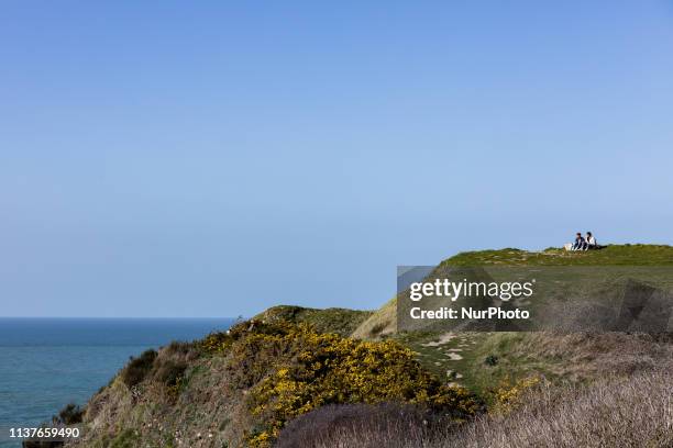 Etretat, Normandy, France, March 25, 2019. A couple contemplates the ocean from the d aval cliff in good weather. Etretat, Normandie, France, le 25...