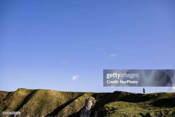 Etretat, Normandy, France, March 25, 2019. A woman walks alone on the aval cliff in good weather. Etretat, Normandie, France, le 25 mars 2019. Une...