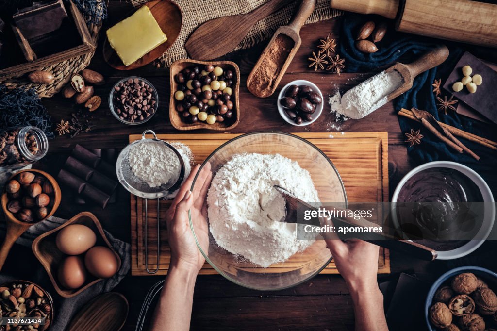 Woman hands making chocolate mousse and cookies on a wooden table in a rustic kitchen