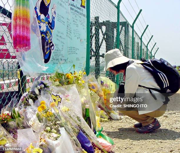 Tomoko Shimizu, a 41-year-old Japanese female office employee offers a bouquet and kneels down before the fence of the Suzuka circuit, where Japanese...