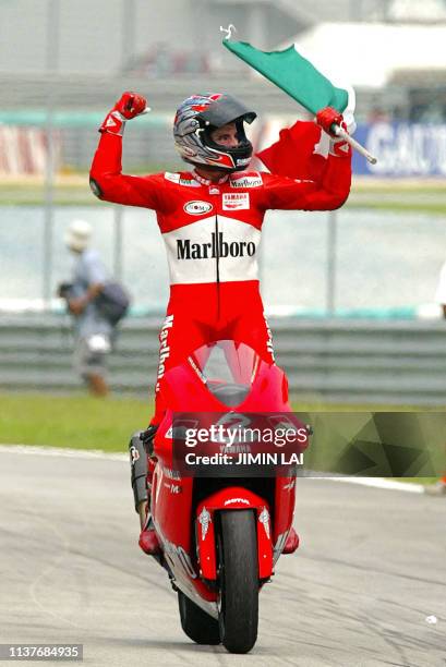 MotoGP rider Italian Max Biaggi celebrates after winning the 2002 Malaysian Motorcycle Grand Prix at the Sepang international circuit, 13 October...