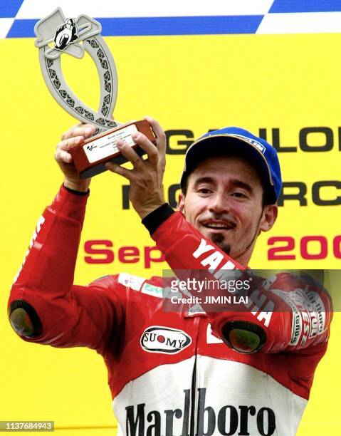 MotoGP rider Italian Max Biaggi raises his trophy after winning the 2002 Malaysian Motorcycle Grand Prix at the Sepang international circuit, 13...