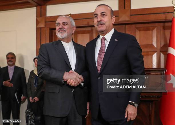 Turkish Foreign Minister Mevlut Cavusoglu and Iranian Foreign Minister Mohammad Javad Zarif shake hands after giving a press conference in Ankara,...