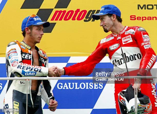 MotoGP rider Italian Max Biaggi shakes hands with his compatriot and world champion Valentino Rossi after winning the 2002 Malaysian Motorcycle Grand...