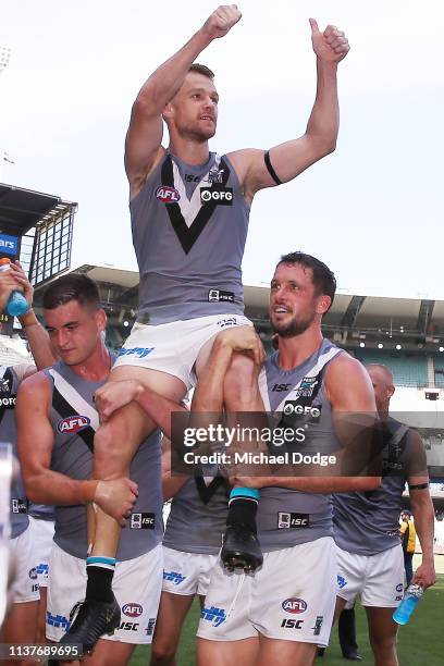 Robbie Gray of the Power is carried off by Tom Rockliff and Travis Boak of the Power after winning his 200th match during the round one AFL match...