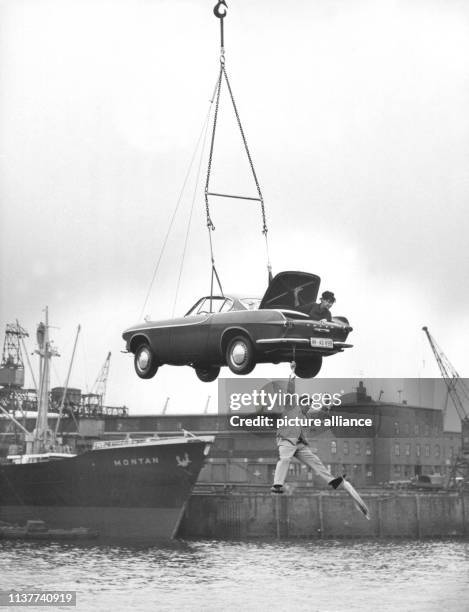 Der Sensationsdarsteller und Stuntman Arnim Dahl hängt mit einer Hand an einem Auto, das an einem Nylonseil von einem Kran auf ein Schiff...
