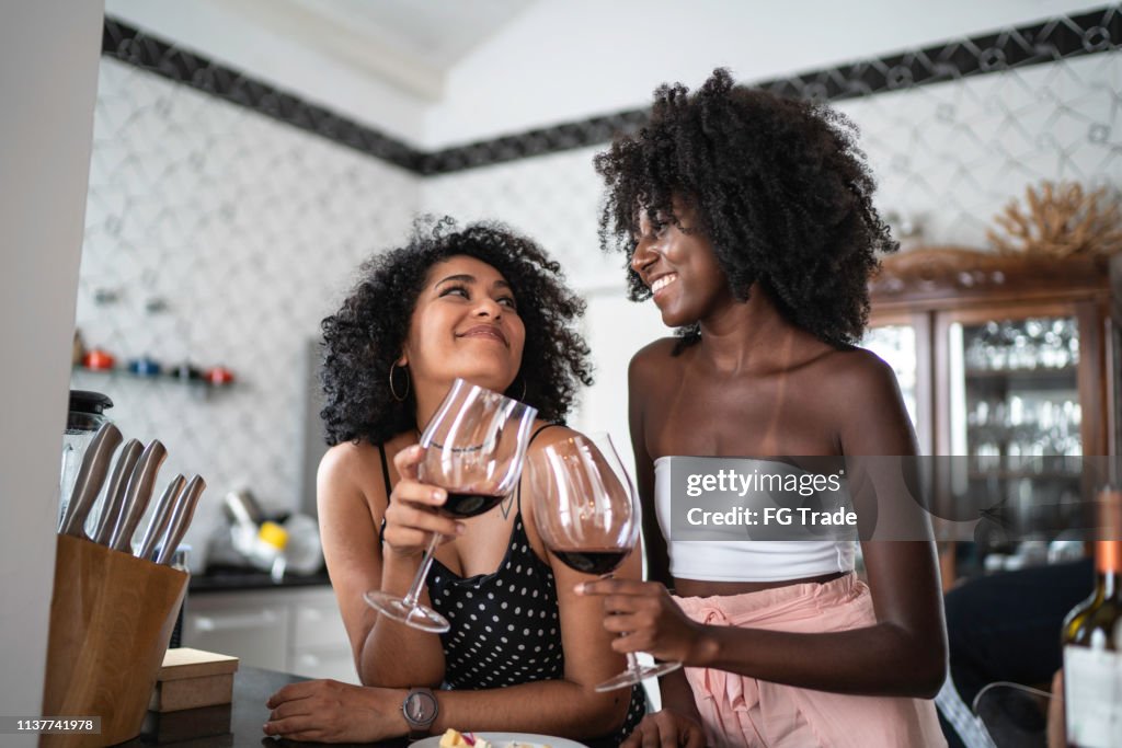 Lesbian Couple or Friends Drinking Wine at Kitchen