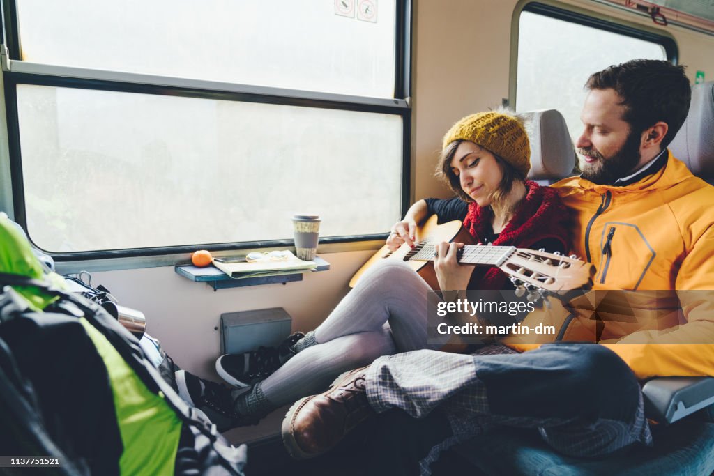 Couple playing the guitar in train