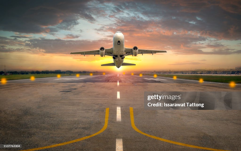 Airplane taking off from the airport runway in beautiful sunset light